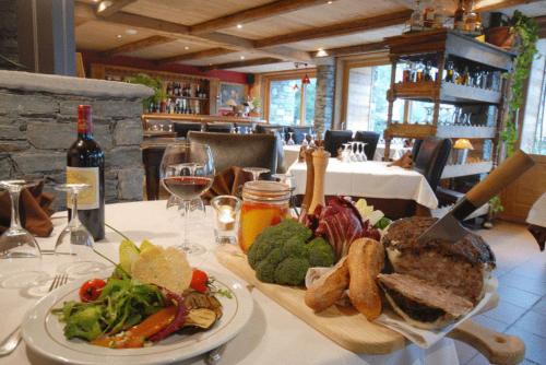 een tafel met een bord eten en een glas wijn bij L'Epicerie Du Monal in Sainte-Foy-Tarentaise