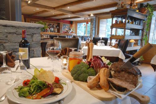 a table with a plate of food and a glass of wine at L'Epicerie Du Monal in Sainte-Foy-Tarentaise