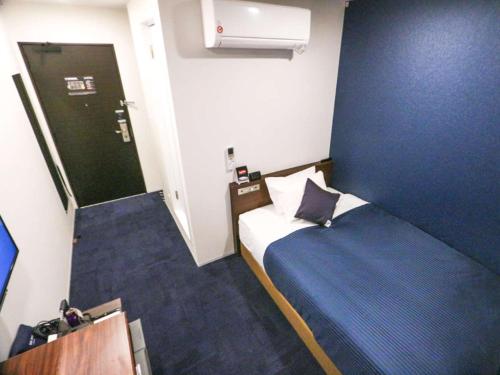 een kleine kamer met een bed en een deur bij HOTEL LiVEMAX Nigata Nagaoka Station in Nagaoka