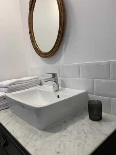 un lavabo blanc dans une salle de bain avec un miroir dans l'établissement L'Autre Maison, à Bozouls