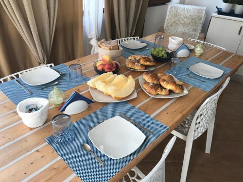 a wooden table with plates of food on it at B&b IL FIOCCO E LA RANDA in San Vito lo Capo