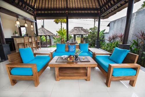 a patio with blue chairs and a table at Villa Cendrawasih Ubud in Tegalalang