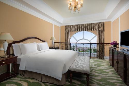 a bedroom with a large white bed and a balcony at Crowne Plaza Ocean Spring Resort, an IHG Hotel in Jimo