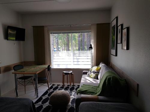 uma sala de estar com um sofá, uma mesa e uma janela em Ylläs Kanerva 107 em Äkäslompolo