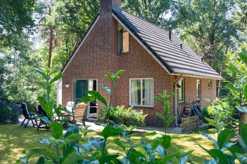 a small red brick house with chairs in the yard at Vosseveen 62 in Zelhem