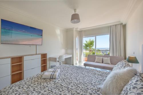 a bedroom with a bed with a television and a couch at Edificio Magna Marbella in Marbella