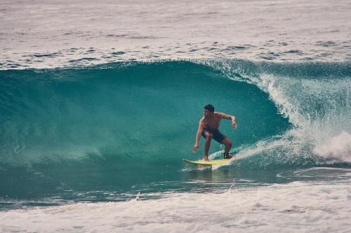 un hombre montando una ola en una tabla de surf en el océano en Playa Los Angeles, en Los Naranjos