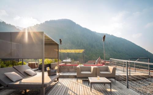 a deck with couches and a view of a mountain at Hotel Valserhof in Valles
