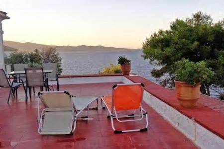 two chairs and a table on a balcony with the water at Tramontana in Hydra