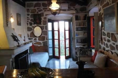 a living room with a fireplace and a stone wall at Tramontana in Hydra