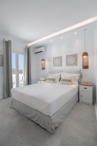 a white bedroom with a large white bed and windows at HORA SUITES in Naxos Chora