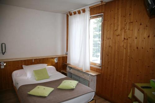 a small bedroom with two beds and a window at Hôtel Le Glacier in Gourette