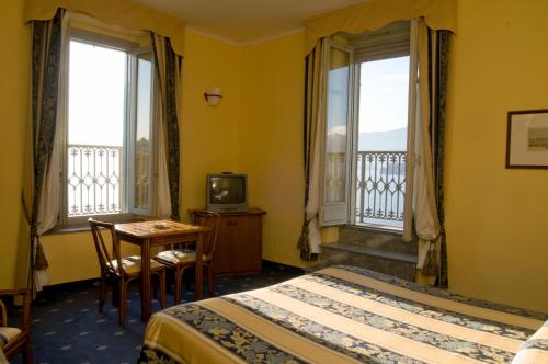ヴェルバーニアにあるEuropalace Hotelのベッド2台、テーブル、窓2つが備わるホテルルームです。