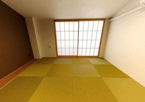an empty room with a large window and a yellow floor at Irori Kyoto Station Higashi-Honganji in Kyoto