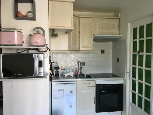 une cuisine avec un réfrigérateur et un micro-ondes dans l'établissement Plage et Mer Service Tout Compris, à Cabourg