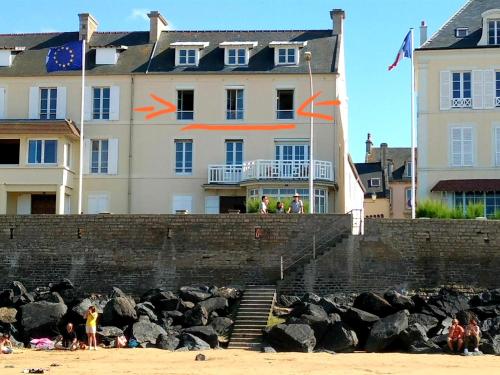 people on the beach in front of a building at Le Phoenix 449 , vue mer, 2 chambres in Arromanches-les-Bains