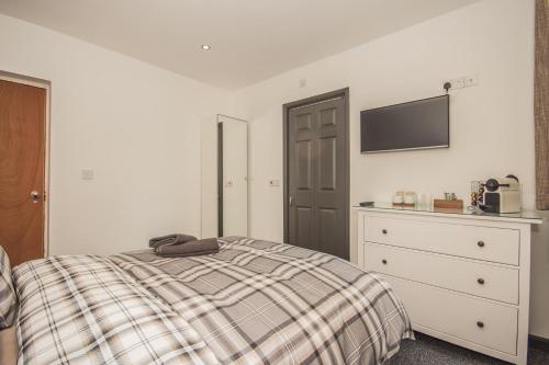 a bedroom with a bed and a dresser and a tv at Featherbed Cottage in Coventry