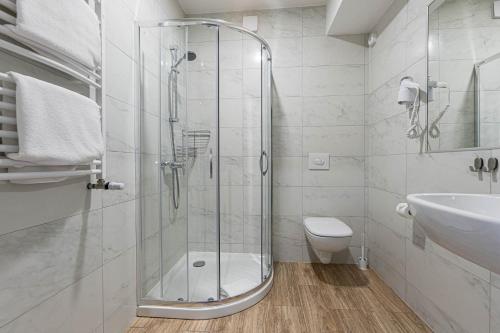 a bathroom with a shower and a toilet and a sink at Akacja Medical Resort in Ciechocinek