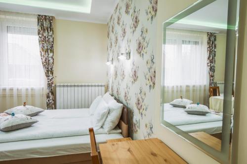 a bedroom with two beds and a mirror at Gita Apartman in Makó