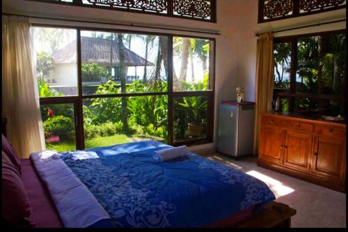 a bedroom with a blue bed and a large window at Jasri Dalem Surf Retreat in Jasri