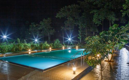 a swimming pool at night with lights at The Sanihara in Vythiri