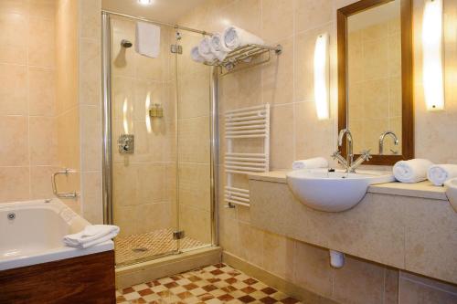 a bathroom with a shower and a sink and a tub at Cliffs of Moher Hotel in Liscannor