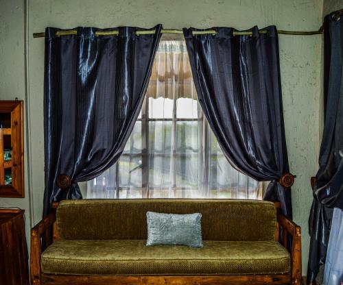 a couch with a pillow sitting in front of a window at Cheetau Lodge in Ebenhaezer