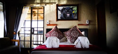 een slaapkamer met een bed met een hondenfoto aan de muur bij Cheetau Lodge in Ebenhaezer