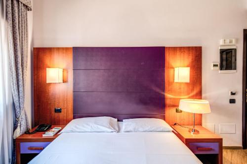a bedroom with a white bed and a purple headboard at Hotel Roma Tiburtina Metro in Rome