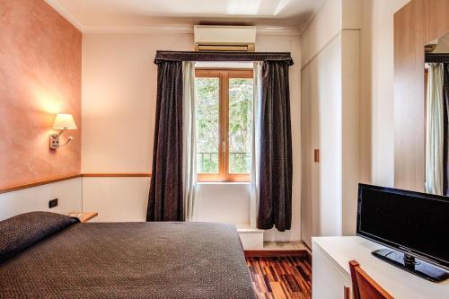 a bedroom with a bed and a television and a window at Hotel Roma Tiburtina Metro in Rome
