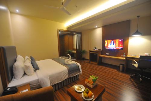 a hotel room with a bed and a flat screen tv at Pipul Padmaja Premium Hotel in Bhubaneshwar