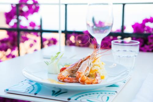 a plate of shrimp on a table with a glass of wine at Hotel Villa Taormina in Taormina