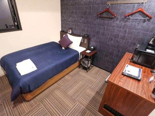a bedroom with a bed and a desk and a television at HOTEL LiVEMAX Nihonbashi Ningyocho in Tokyo
