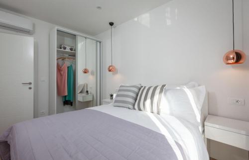 a white bedroom with a bed and a closet at IvMaLu Apartments in Tučepi