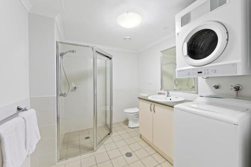 a bathroom with a shower and a washing machine at Club Wyndham Flynns Beach, Trademark Collection by Wyndham in Port Macquarie