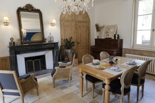 a dining room with a table and chairs and a fireplace at Au Souffle de Vert in Bouvaincourt-sur-Bresle