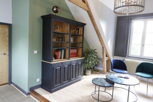 a room with a book shelf and two chairs and a table at Au Souffle de Vert in Bouvaincourt-sur-Bresle