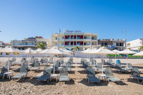 a group of chairs and umbrellas on a beach at Olympic Suites in Rethymno