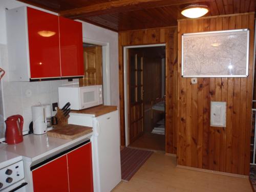 a kitchen with red cabinets and a white microwave at Apartmány Korenko in Štrba