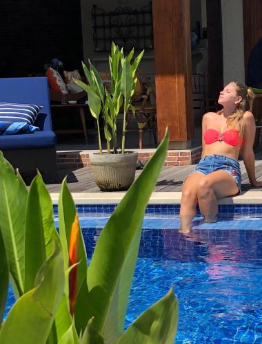 a woman in a bikini sitting next to a swimming pool at Puri Kasih Gottlieb in Ubud