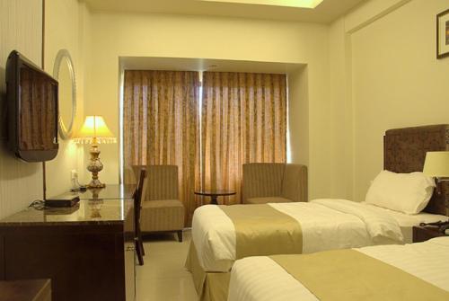 a hotel room with two beds and a desk at Pramod Convention & Club Resort in Cuttack