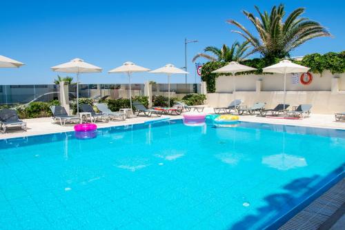 a large swimming pool with chairs and umbrellas at Olympic Suites in Rethymno Town