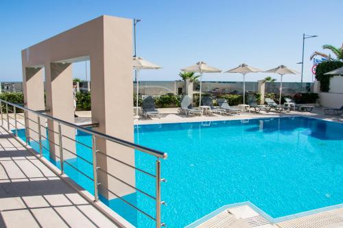 a swimming pool at a hotel with chairs and umbrellas at Olympic Suites in Rethymno Town