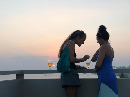 two women standing on a ledge with glasses of wine at Lighthouse Ahangama in Ahangama