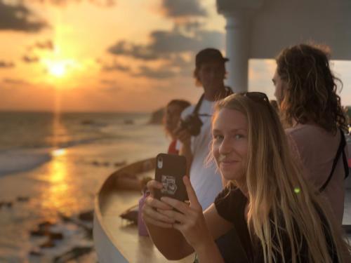 a girl taking a picture with her cell phone on the beach at Lighthouse Ahangama in Ahangama