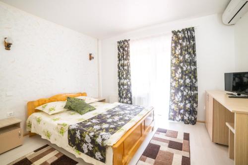 a bedroom with a bed and a large window at Pensiunea Versant in Băile Herculane