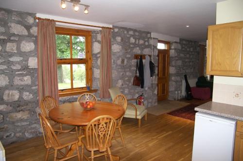a kitchen and dining room with a wooden table and chairs at West Gorton in Grantown on Spey