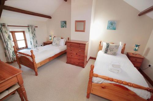 a bedroom with two twin beds and a desk at Cilhendre Holiday Cottages - The Old Cowshed in Swansea