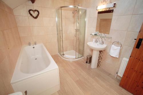 a bathroom with a shower and a tub and a sink at Cilhendre Holiday Cottages - The Old Cowshed in Swansea