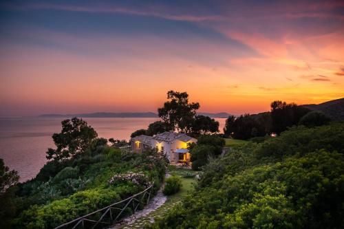 una casa en una colina con vistas al océano al atardecer en Angolo di paradiso sul mare, en Geremèas